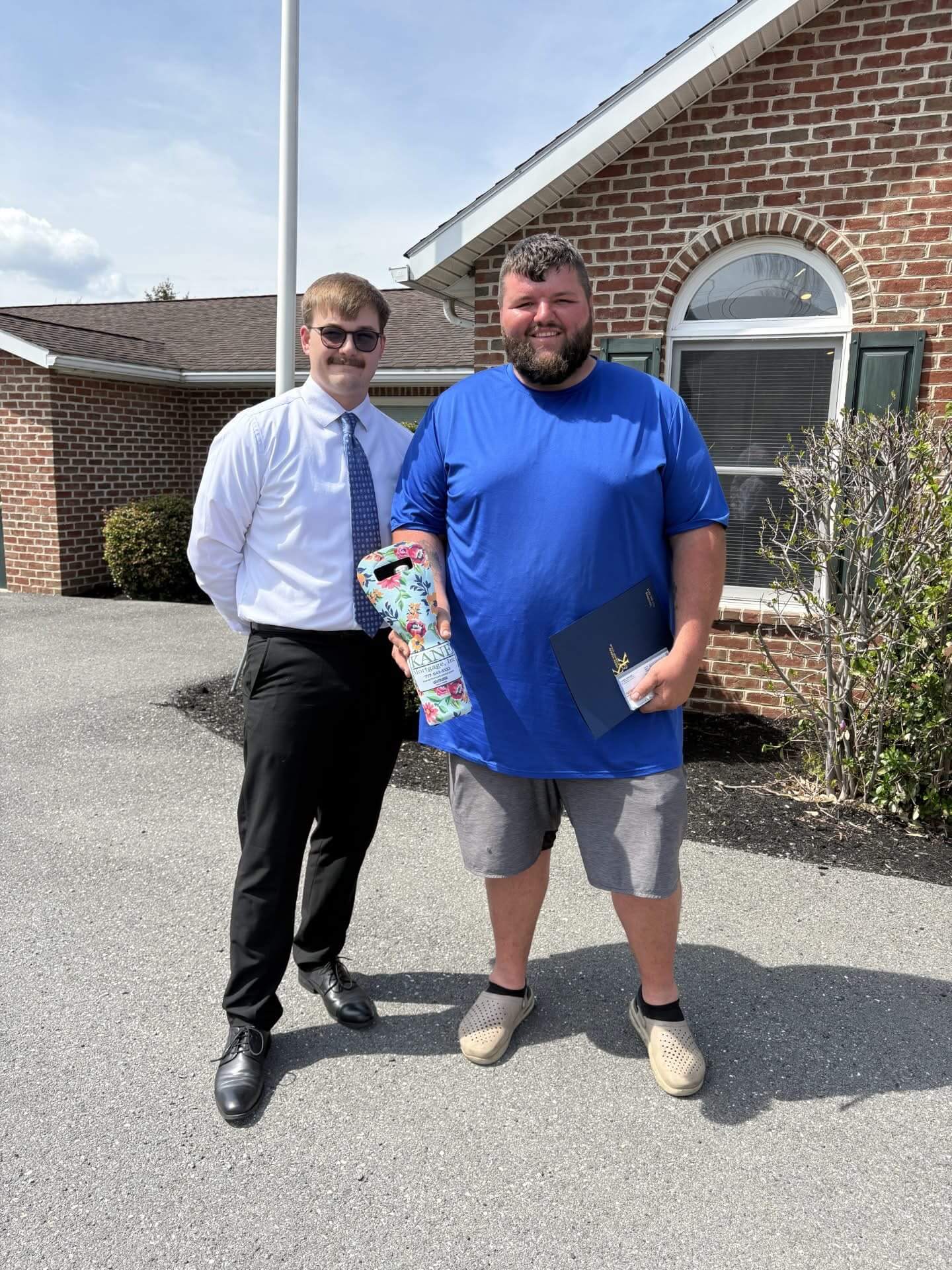 A happy client celebrates with Keegan outside the Kane Mortage office.